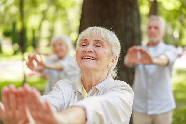 seniors practice tai chi outside on a nice day