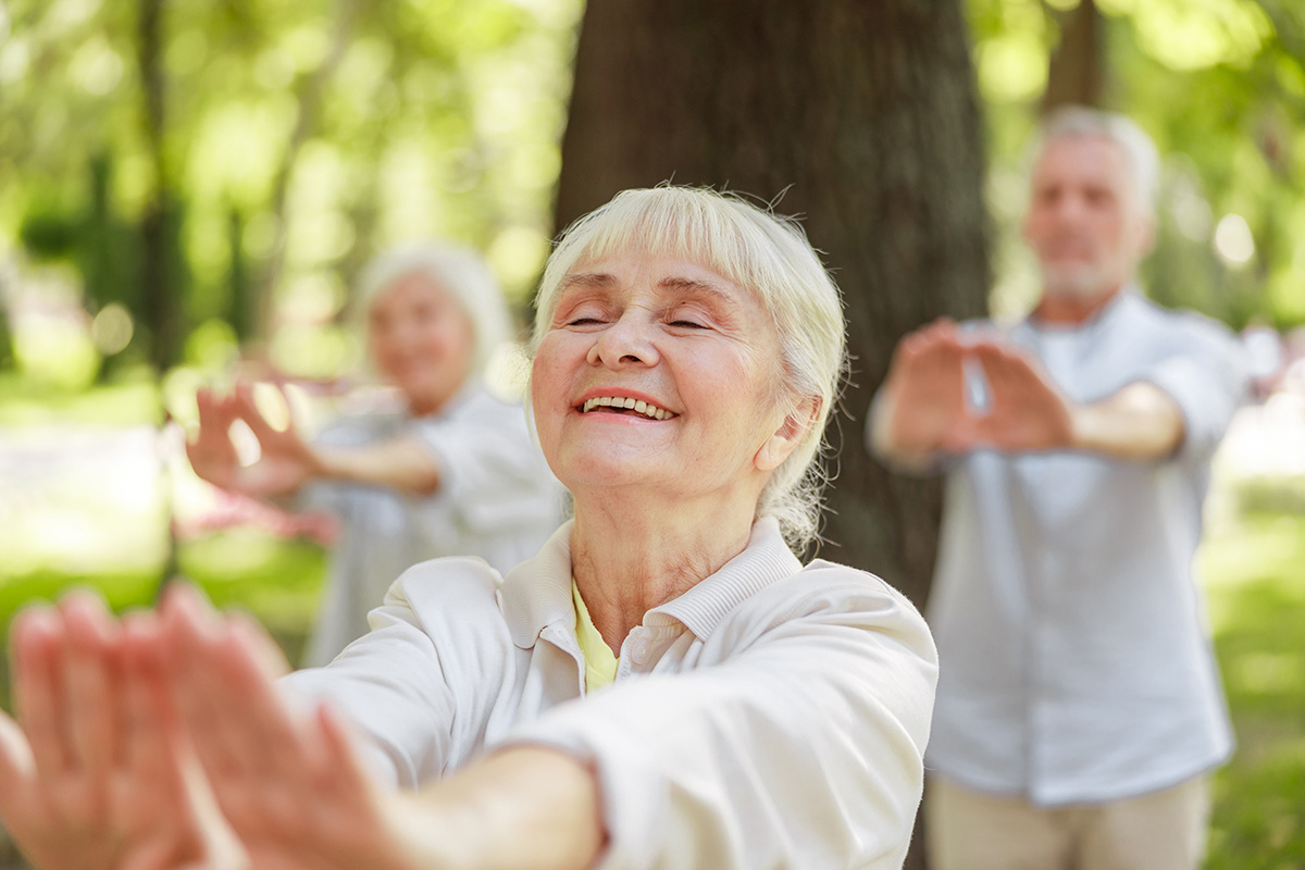 seniors practice tai chi outside on a nice day