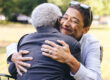 a young woman smiles s she hugs her senior loved one